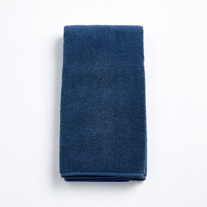 Folded indigo blue hand towel made of soft, textured cotton terry cloth on a white background.