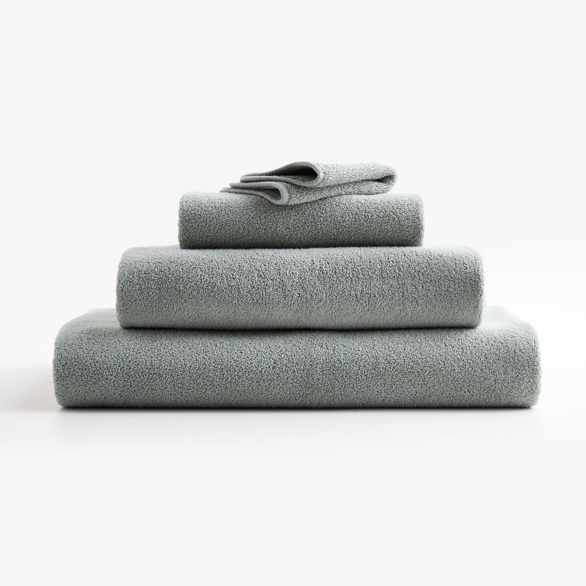 Stacked mist blue HG Signature zero-twist cotton bath sheets and towels with piped edges.