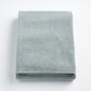 Folded mist blue Signature bath sheet in plush, absorbent cotton terry fabric on a white background.