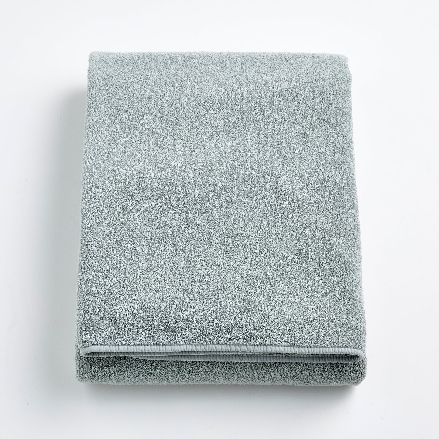 Folded mist blue Signature bath sheet in plush, absorbent cotton terry fabric on a white background.