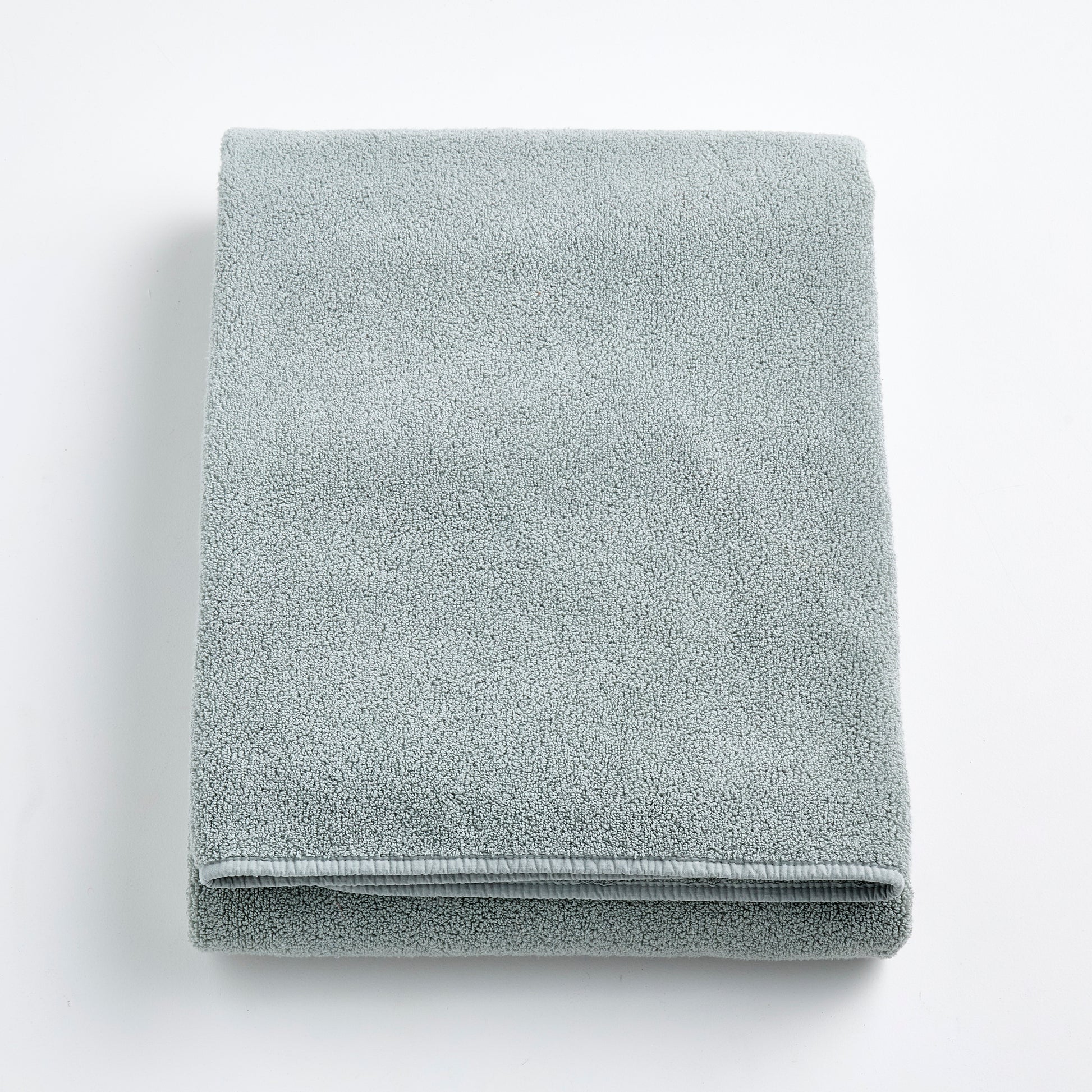 Folded mist blue Signature bath sheet in plush, absorbent cotton terry fabric on a white background.