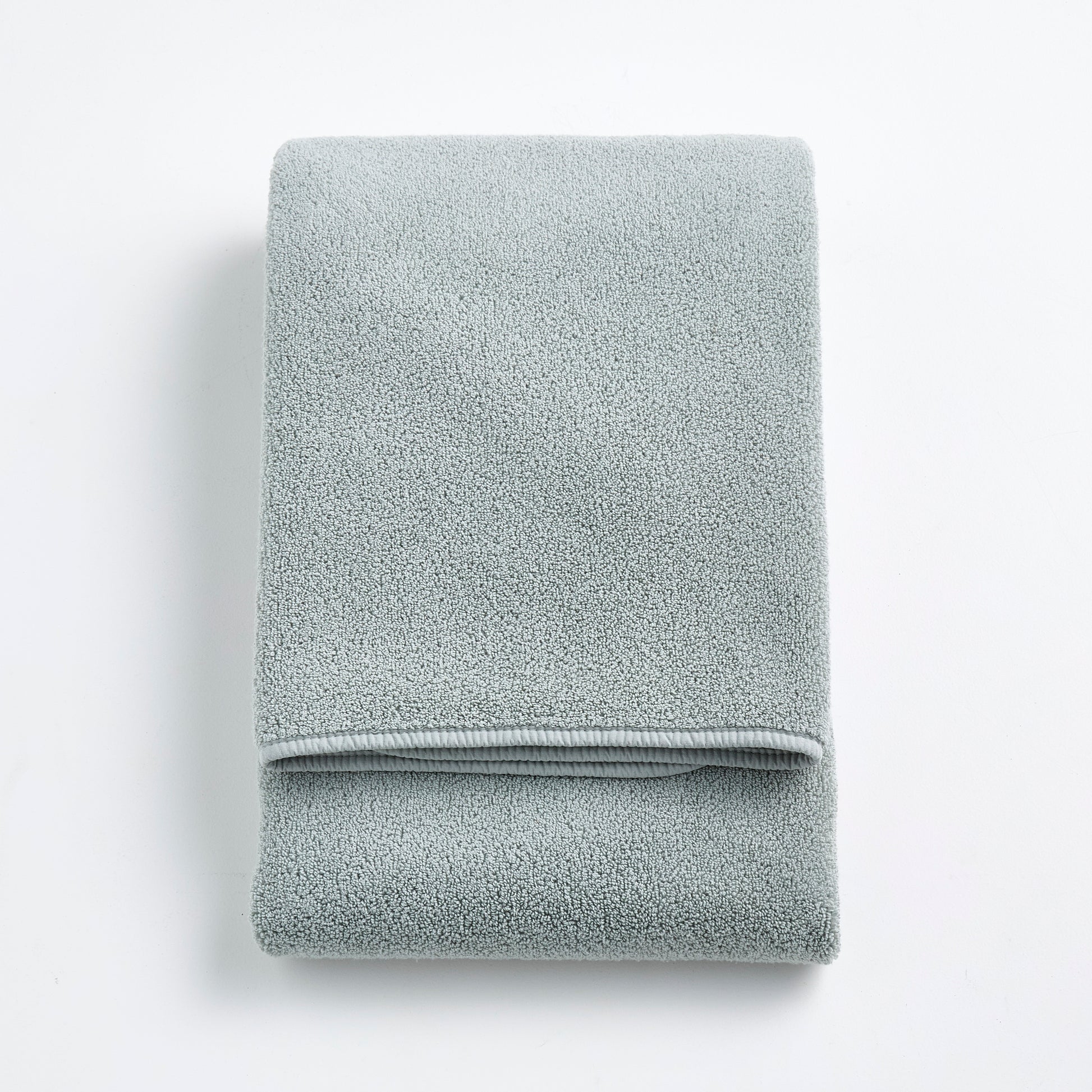 Folded mist blue Signature bath towel with a soft, plush cotton texture on a white background.