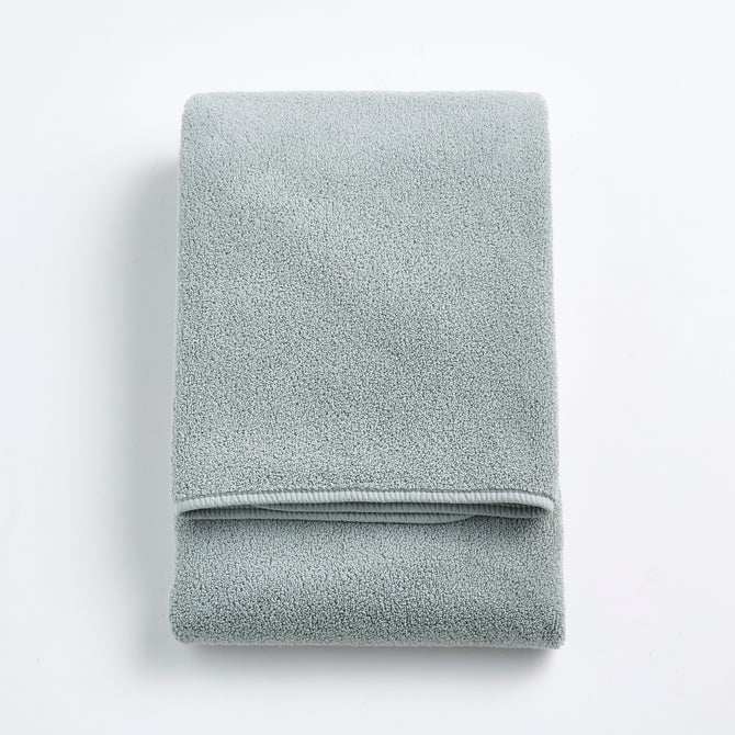 Folded mist blue Signature bath towel with a soft, plush cotton texture on a white background.