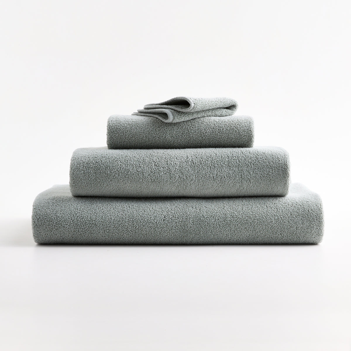 Stack of soft Mist Blue zero-twist cotton towels with piped edges from the Hudson Grace Signature collection.