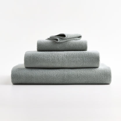 Stack of soft Mist Blue zero-twist cotton towels with piped edges from the Hudson Grace Signature collection.