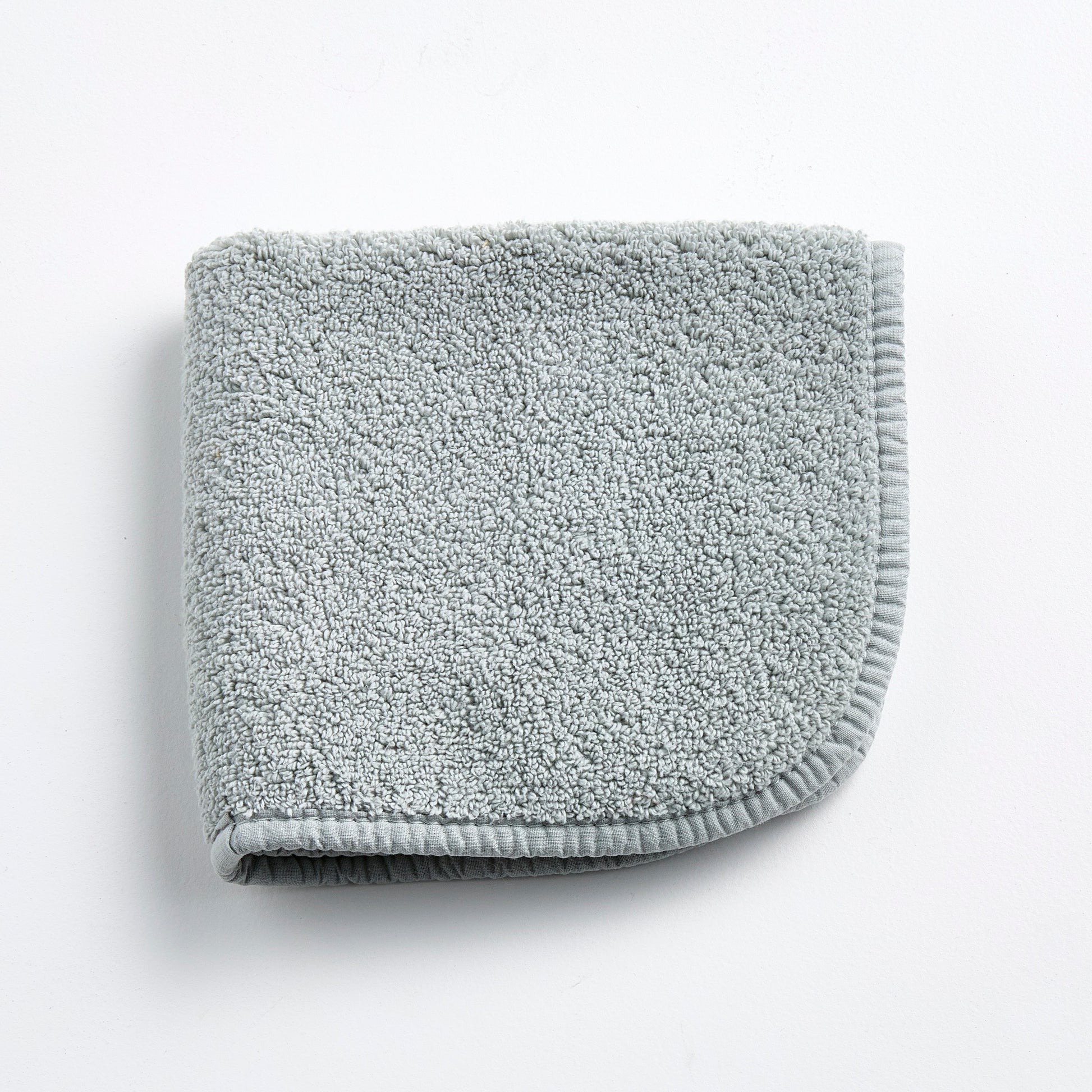 Mist blue Signature washcloth in soft, textured cotton terry with a finished fabric edge on a white background.