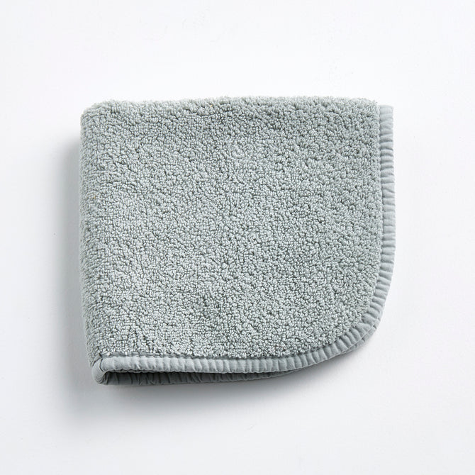Mist blue Signature washcloth in soft, textured cotton terry with a finished fabric edge on a white background.