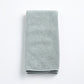 Folded mist blue Signature hand towel made of soft, plush cotton terry fabric on a white background.
