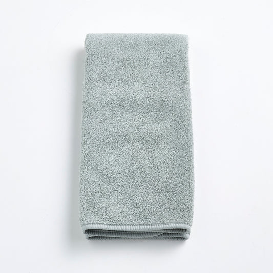 Folded mist blue Signature hand towel made of soft, plush cotton terry fabric on a white background.