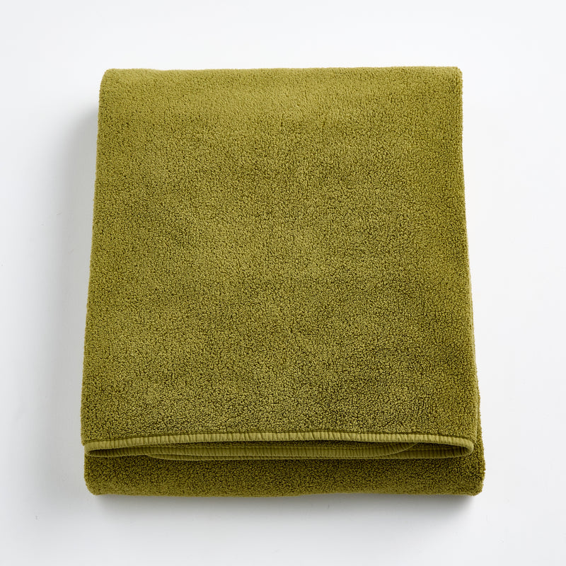 Folded olive green HG Signature bath sheet made of zero-twist cotton with matching bias piping.