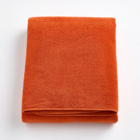 Folded pumpkin orange Signature bath sheet made of plush, absorbent cotton terry fabric.