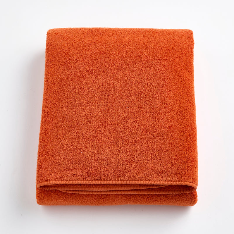 Folded pumpkin orange Signature bath sheet made of plush, absorbent cotton terry fabric.