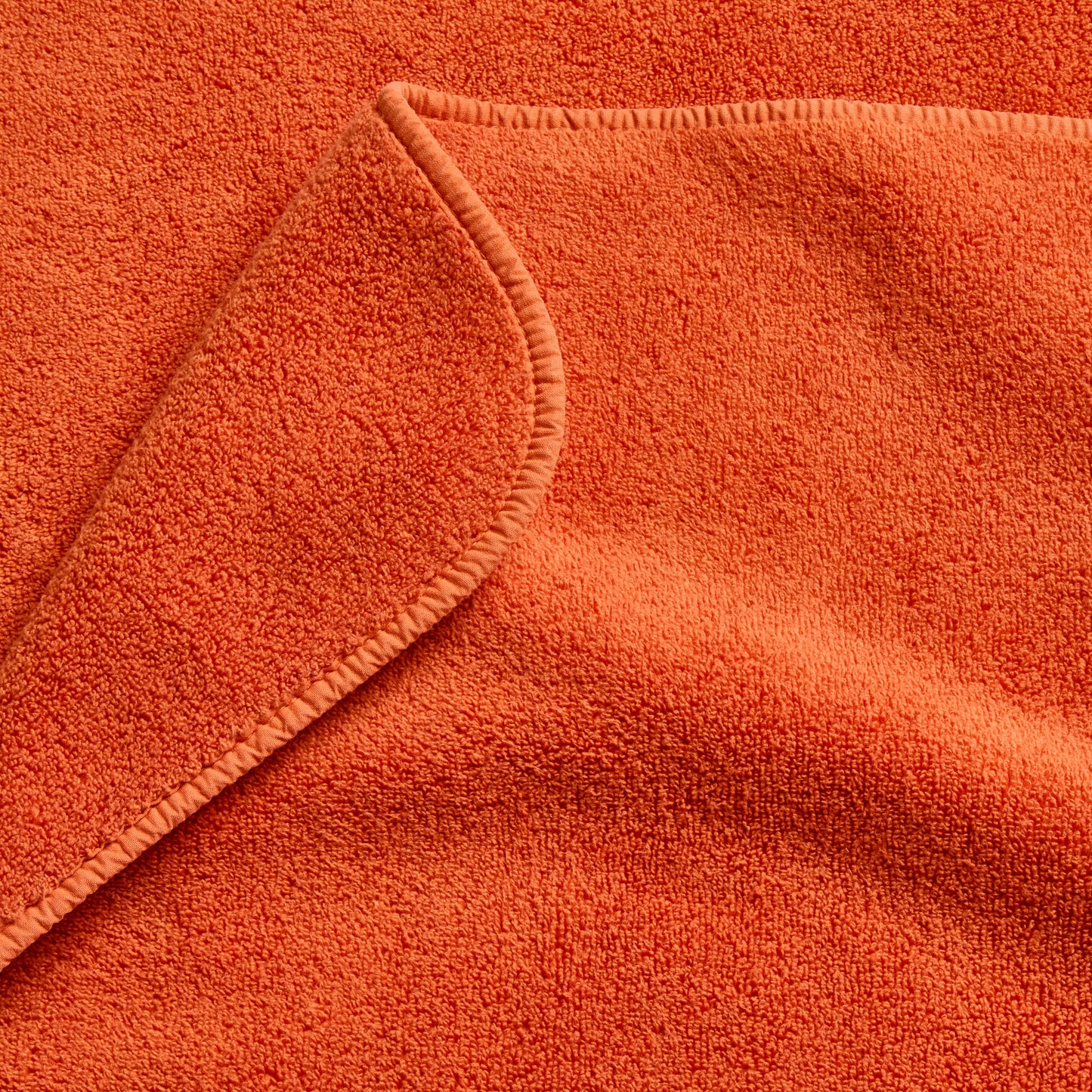 Pumpkin orange Signature bath towel with a soft, plush cotton terry texture and a finished stitched edge.