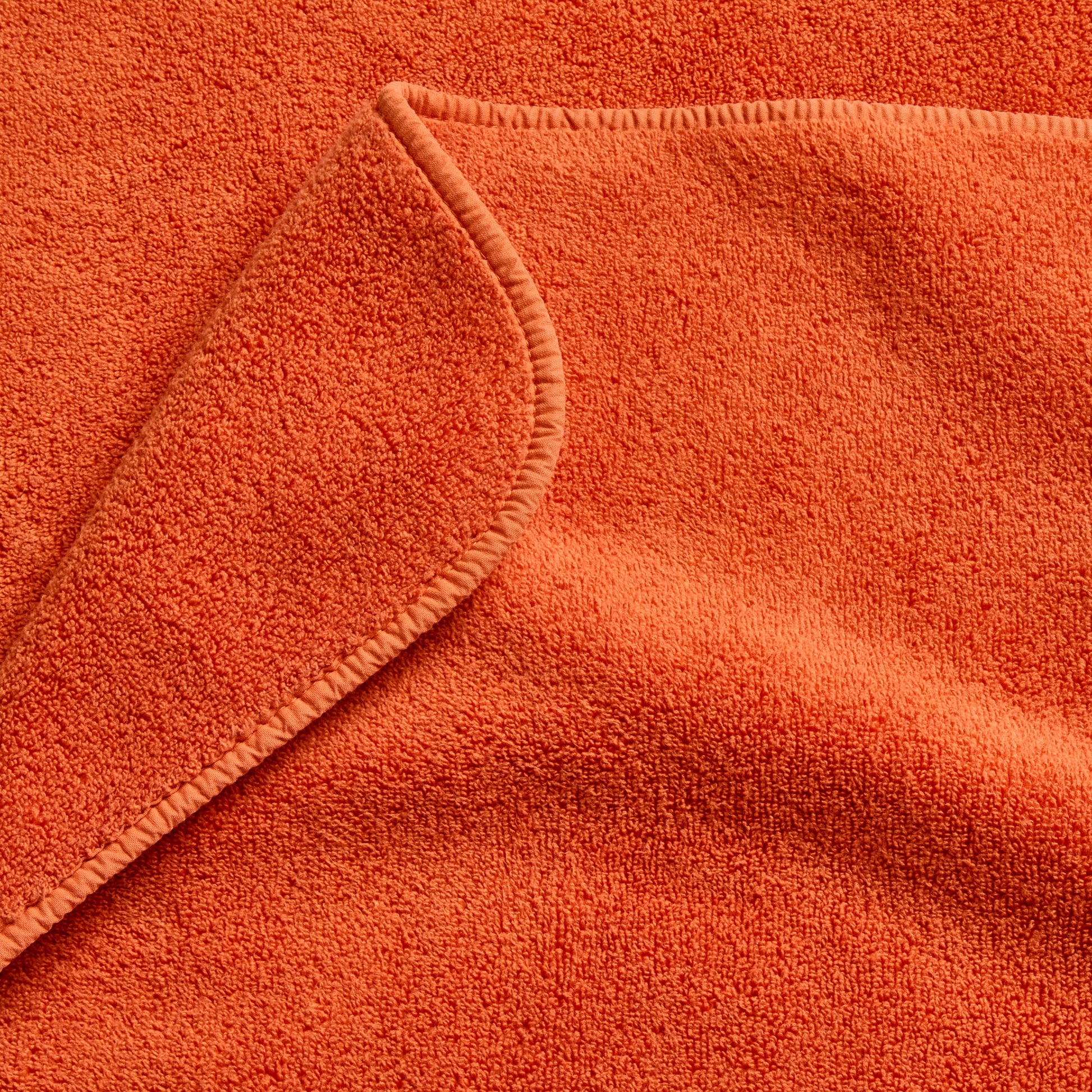 Pumpkin orange Signature bath towel with a soft, plush cotton terry texture and a finished stitched edge.
