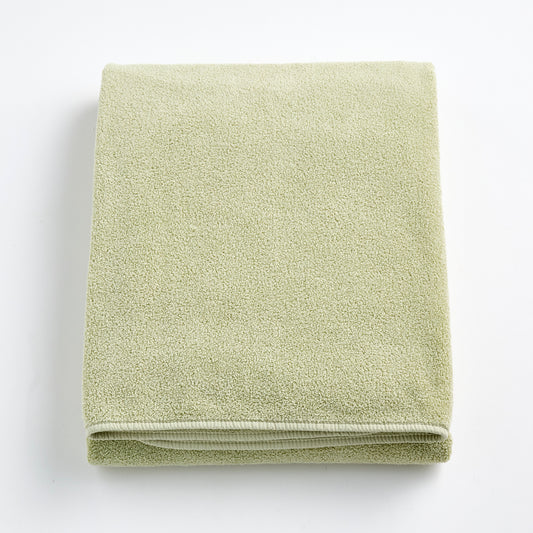 Folded sage green Signature bath sheet made of plush, absorbent cotton terry fabric.