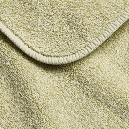 Sage green Signature bath towel featuring a soft, absorbent cotton terry texture and a finished stitched edge.