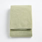 Folded sage green Signature bath towel made of soft, textured cotton terry fabric on a white background.