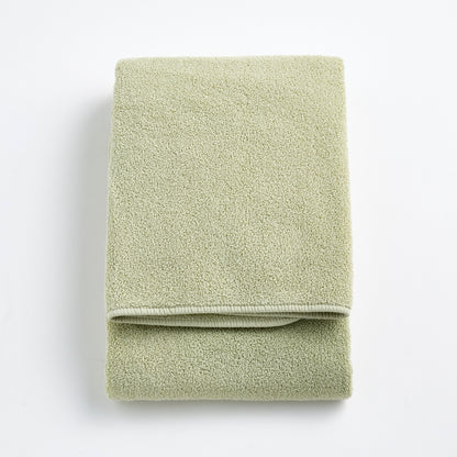 Folded sage green Signature bath towel made of soft, textured cotton terry fabric on a white background.