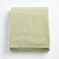 Folded sage green Signature bath sheet made of plush, absorbent cotton terry fabric.