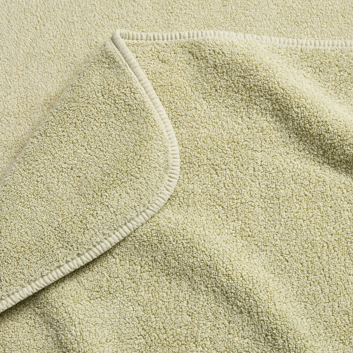 Sage green cotton hand towel with a soft, textured terry cloth finish and a neatly stitched rounded hem.