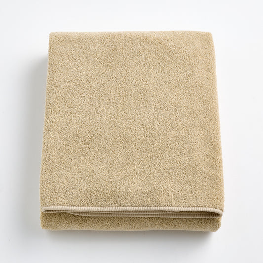 Folded sand-colored Signature bath sheet in plush, absorbent cotton terry fabric with a clean hemmed edge.