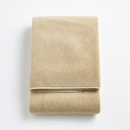 Folded sand-colored Signature bath towel in plush, high-quality cotton terry fabric with a clean hemmed edge.