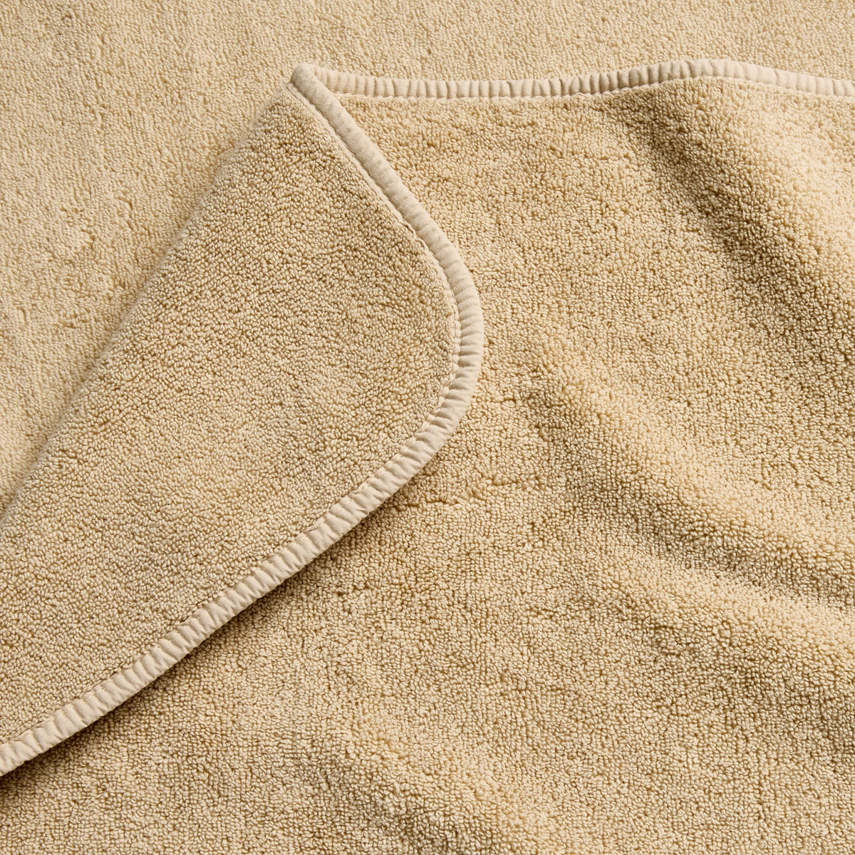 Sand-colored Signature bath sheet in plush, absorbent cotton terry fabric with a finished hemmed edge.