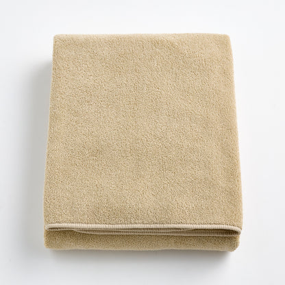 Folded sand-colored Signature bath sheet in plush, absorbent cotton terry fabric with a clean hemmed edge.