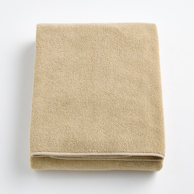 Folded sand-colored Signature bath sheet in plush, absorbent cotton terry fabric with a clean hemmed edge.