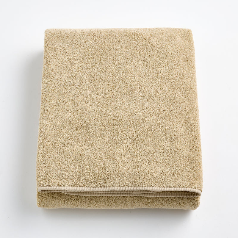 Folded sand-colored Signature bath sheet in plush, absorbent cotton terry fabric with a clean hemmed edge.