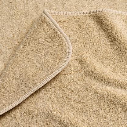 Sand-colored Signature bath towel featuring a soft, plush cotton terry texture and a neatly finished hemmed edge.