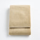 Folded sand-colored Signature bath towel in plush, high-quality cotton terry fabric with a clean hemmed edge.