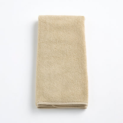 Folded sand-colored Signature hand towel made of plush, absorbent cotton terry fabric on a white background.