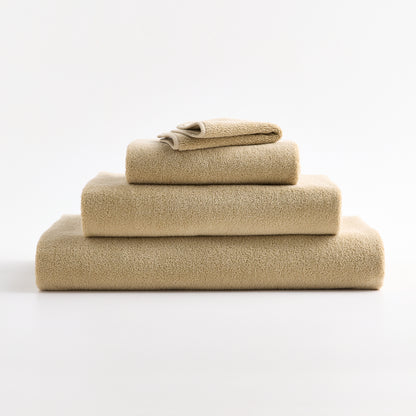 Stacked HG Signature sand-colored zero-twist cotton washcloths with piped edges.