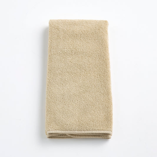 Folded sand-colored Signature hand towel made of plush, absorbent cotton terry fabric on a white background.