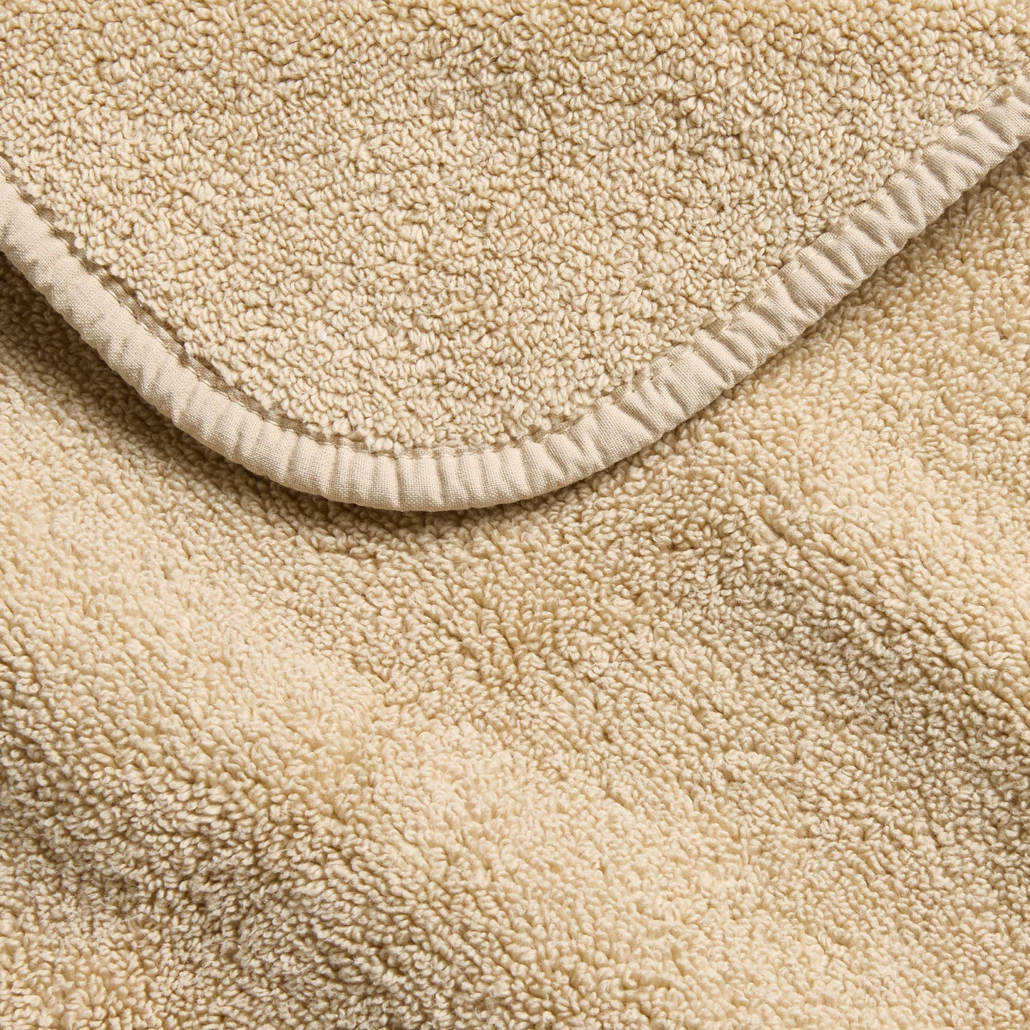 Sand-colored Signature washcloth with a soft, plush terry texture and a neatly finished stitched edge.