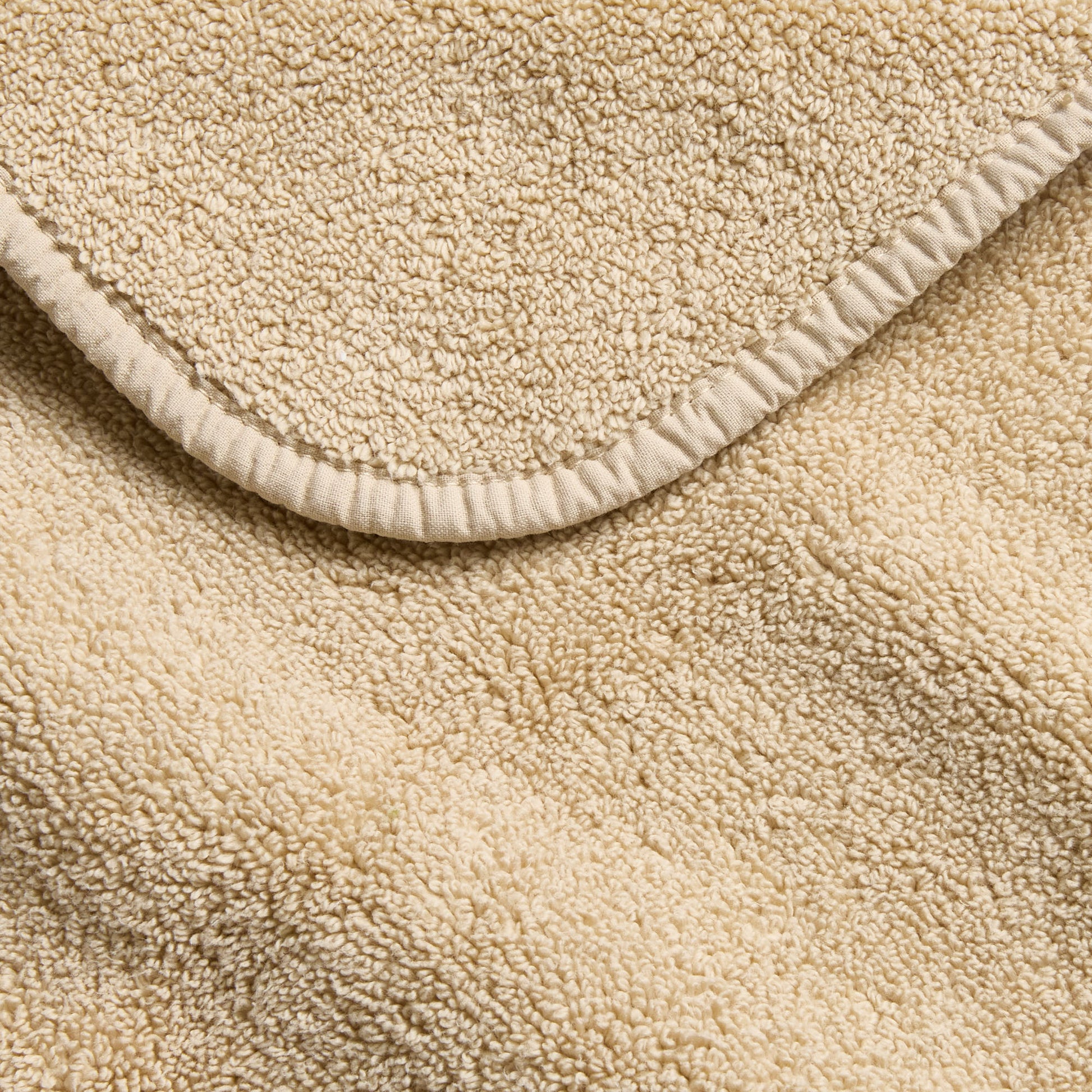 Sand-colored Signature washcloth with a soft, plush terry texture and a neatly finished stitched edge.