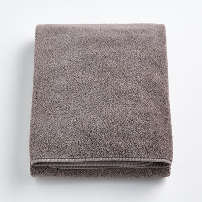 Folded stone gray bath sheet made of plush, absorbent cotton terry fabric with a clean hemmed edge.
