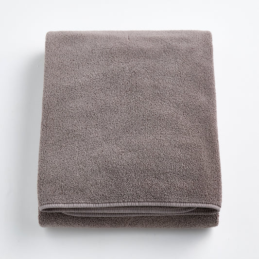 Folded stone gray bath sheet made of plush, absorbent cotton terry fabric with a clean hemmed edge.