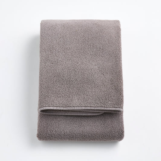 Folded stone gray Signature bath towel in plush, high-quality cotton terry fabric on a white background.
