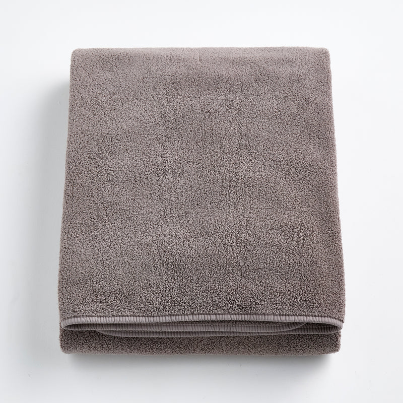 Folded stone gray bath sheet made of plush, absorbent cotton terry fabric with a clean hemmed edge.