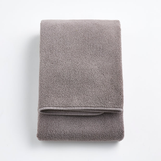 Folded stone gray Signature bath towel in plush, high-quality cotton terry fabric on a white background.