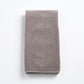 Folded stone gray Signature hand towel made of plush, textured cotton fabric on a white background.