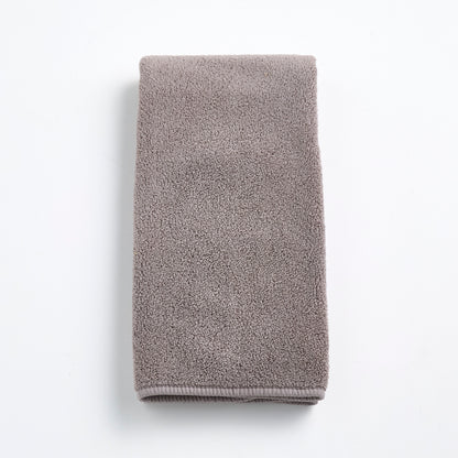 Folded stone gray Signature hand towel made of plush, textured cotton fabric on a white background.