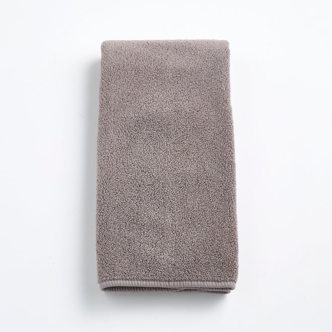 Folded stone gray Signature hand towel made of plush, textured cotton fabric on a white background.