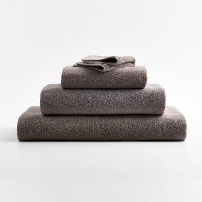 Stacked stone gray HG Signature zero-twist cotton washcloths and towels with piped edges.