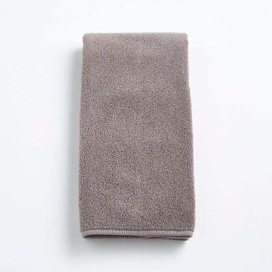 Folded stone gray Signature hand towel made of plush, textured cotton fabric on a white background.