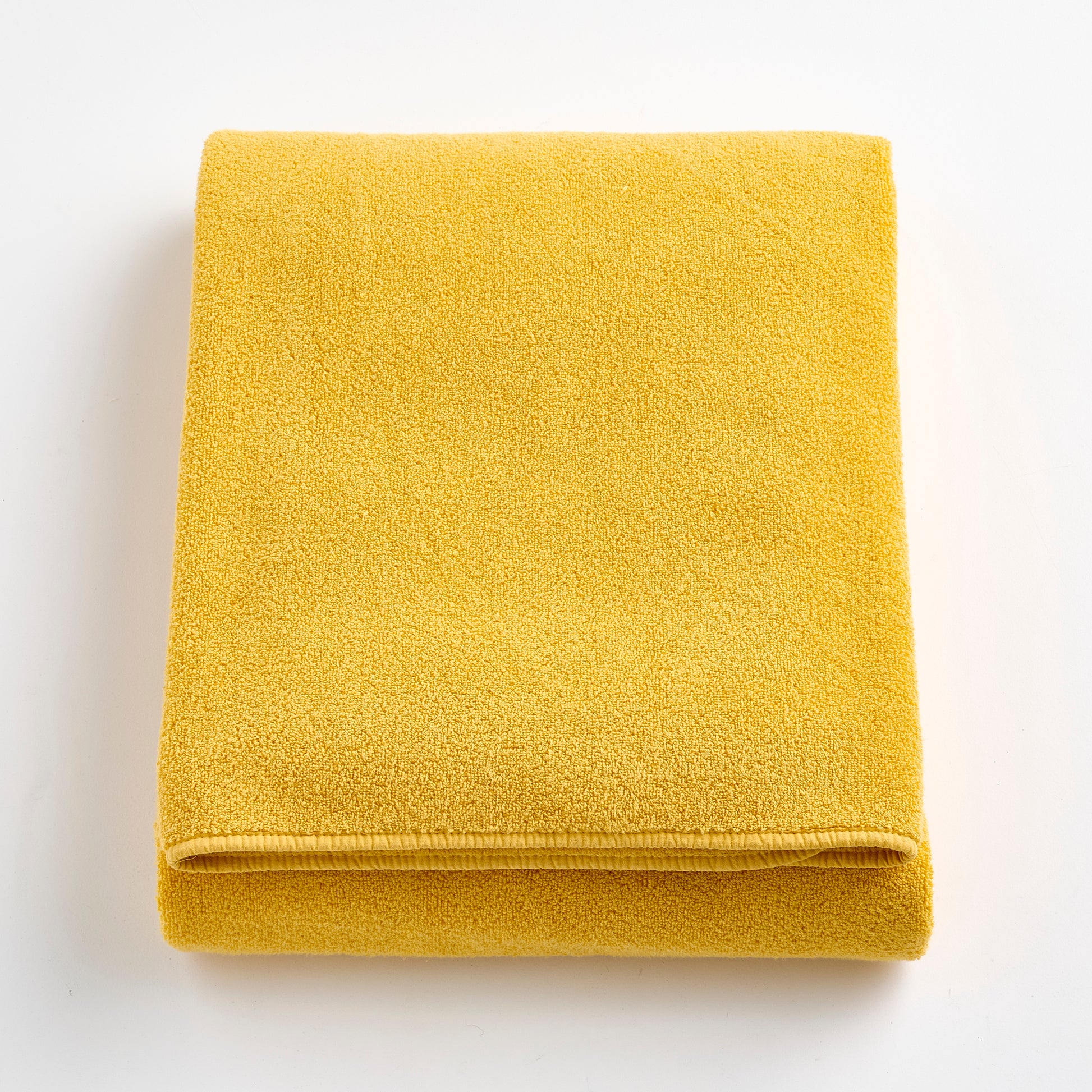 Folded bright yellow Signature bath sheet made of soft, absorbent cotton terry fabric.