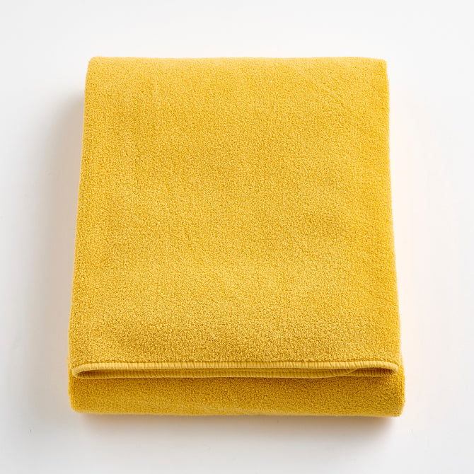 Folded bright yellow Signature bath sheet made of soft, absorbent cotton terry fabric.