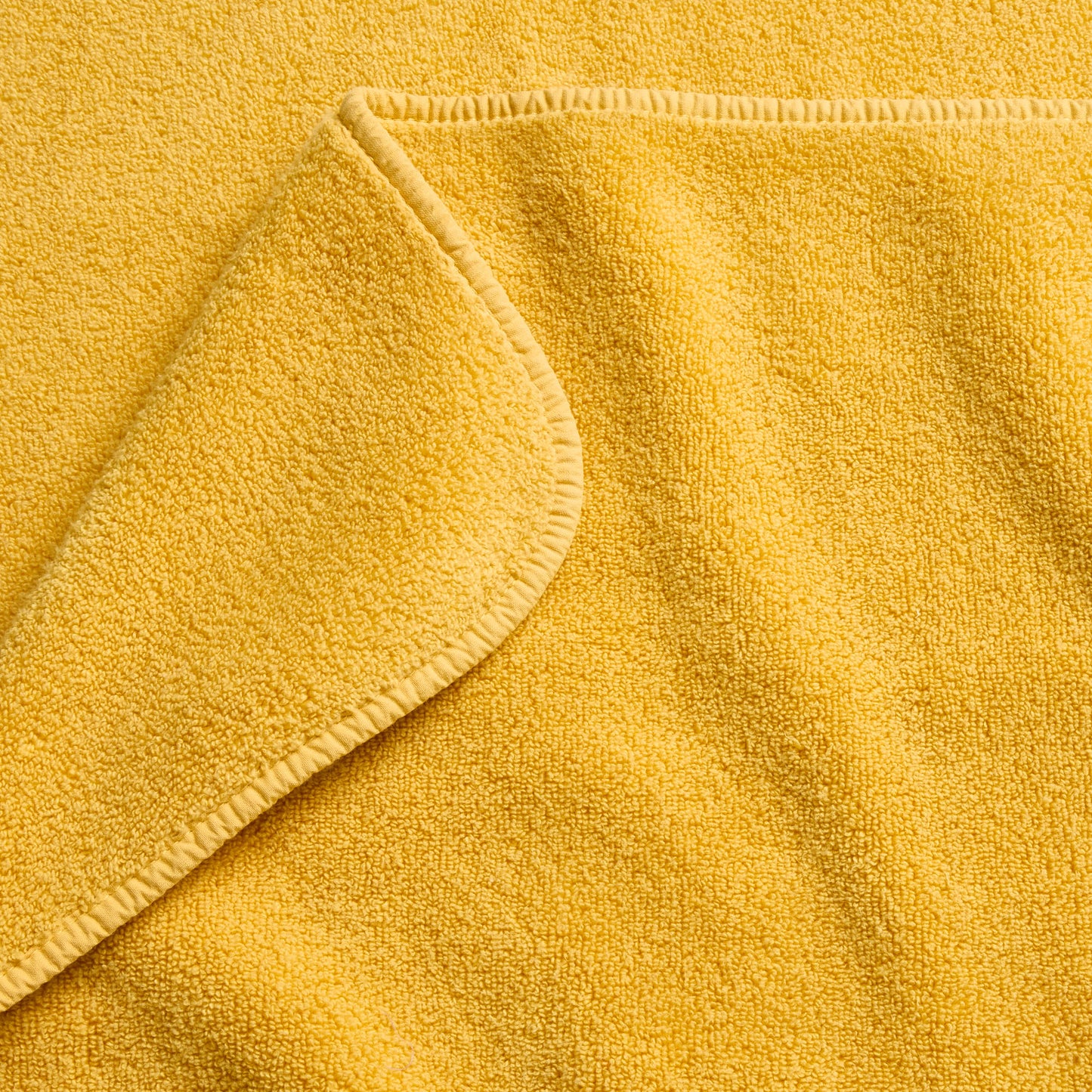 Bright yellow cotton bath towel with a soft, absorbent terry cloth texture and finished stitched edges.